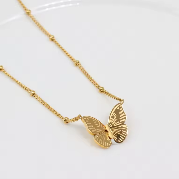 Gold butterfly necklace on a white background